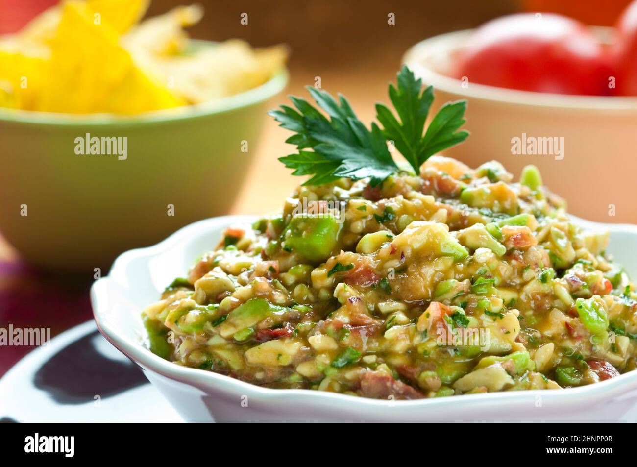 Guacamole-Salat in Schüssel weiß mit Petersilie obenauf angeordnet Stockfoto