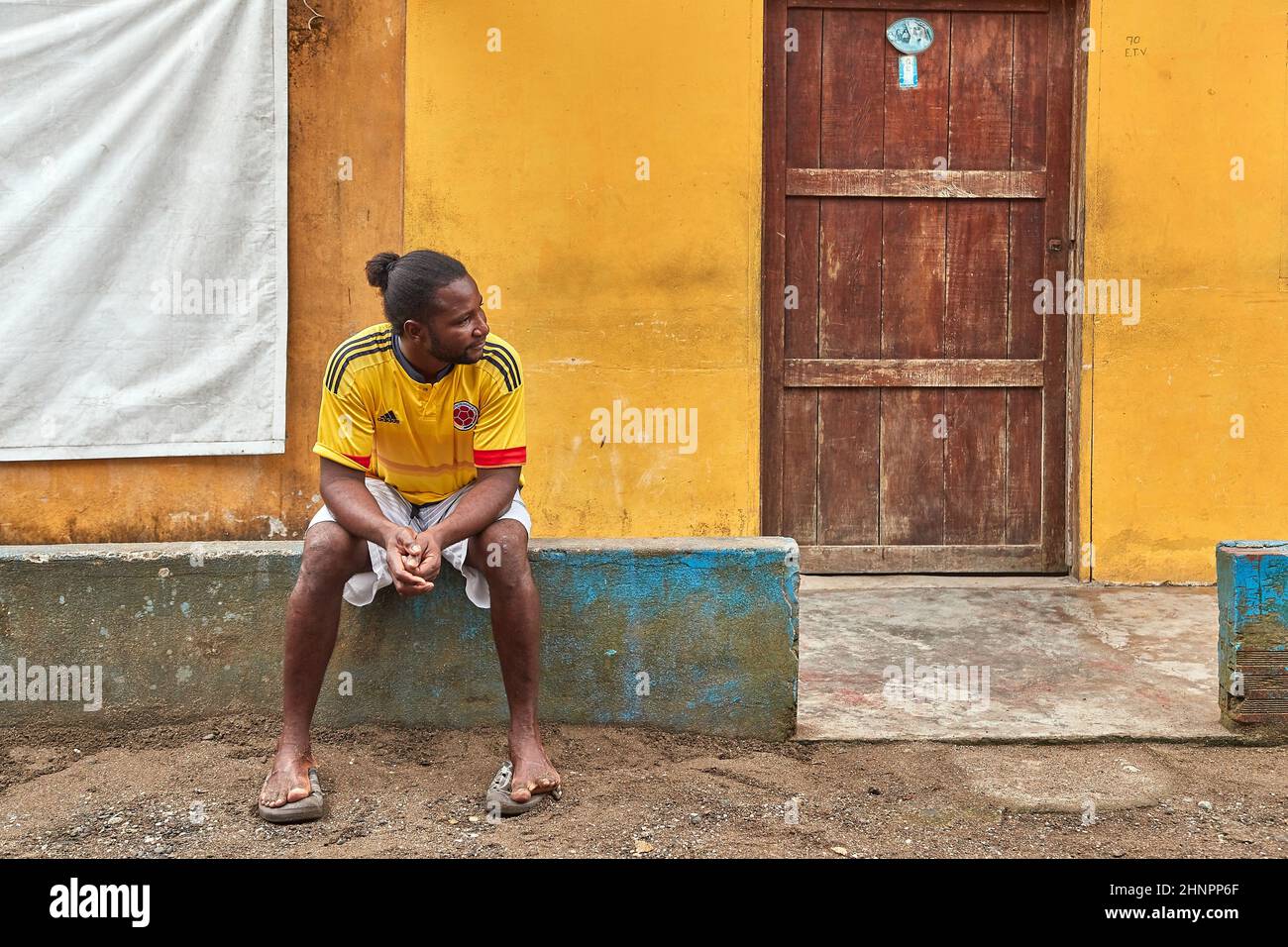 Abgelegenes Dorf in Kolumbien, Mann sitzt vor dem Haus Stockfoto