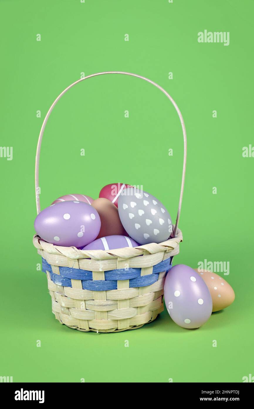 Kleiner osterkorb mit bunten Eiern auf grünem Hintergrund Stockfoto