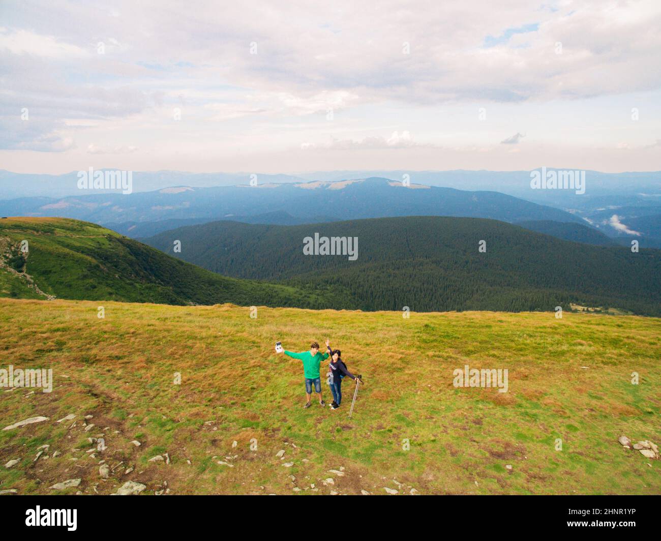 Luftaufnahme des Great Green Ridge. Guy und Girl stehen auf einem großen Hügel vor dem Hintergrund einer riesigen Berglandschaft Stockfoto