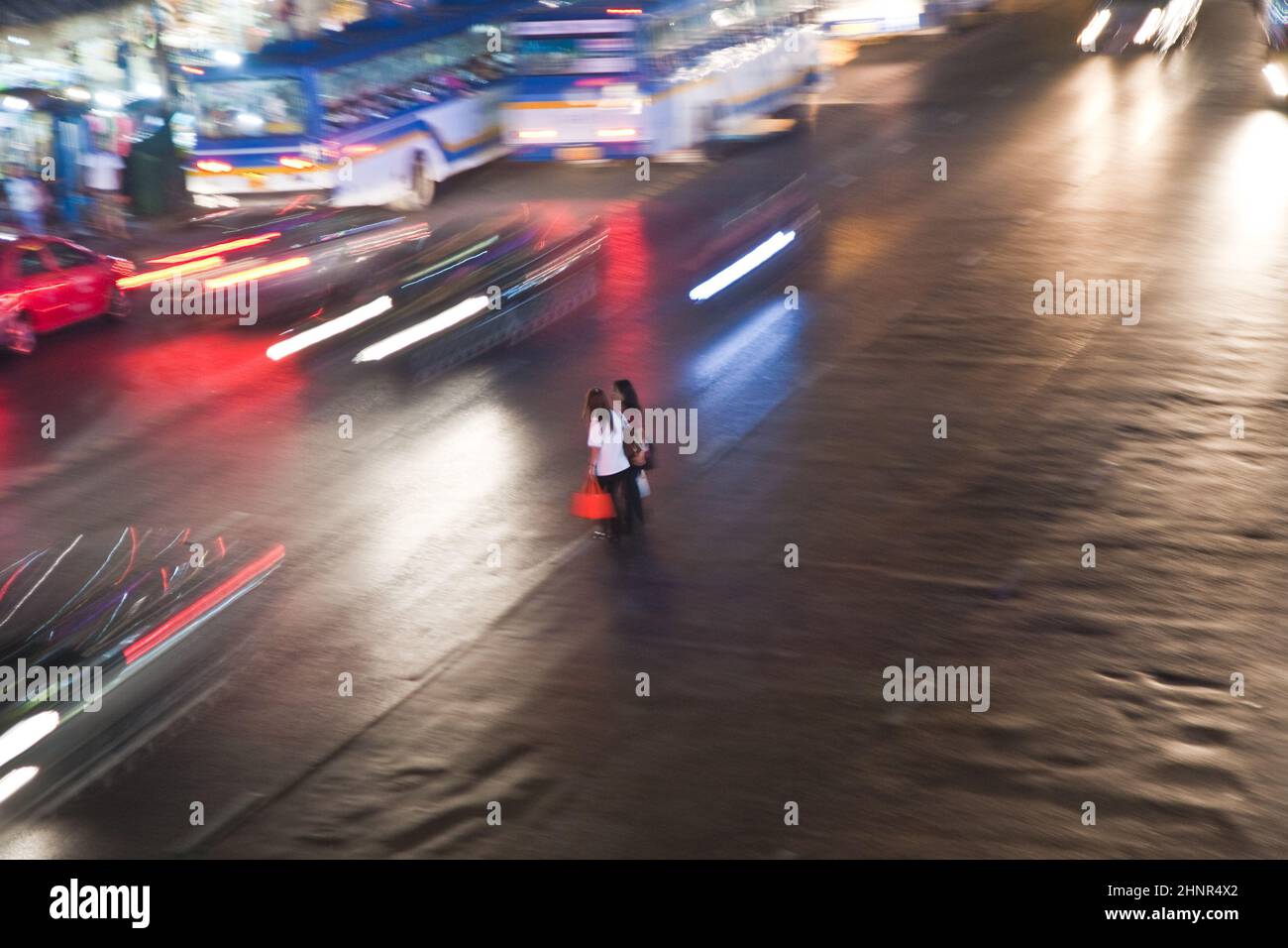 Frauen überqueren nachts eine Hauptstraße in Bangkok Stockfoto