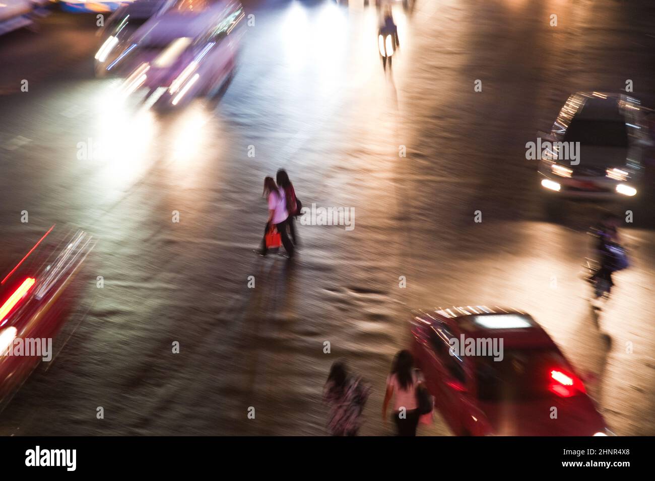 Frauen überqueren nachts eine Hauptstraße in Bangkok Stockfoto