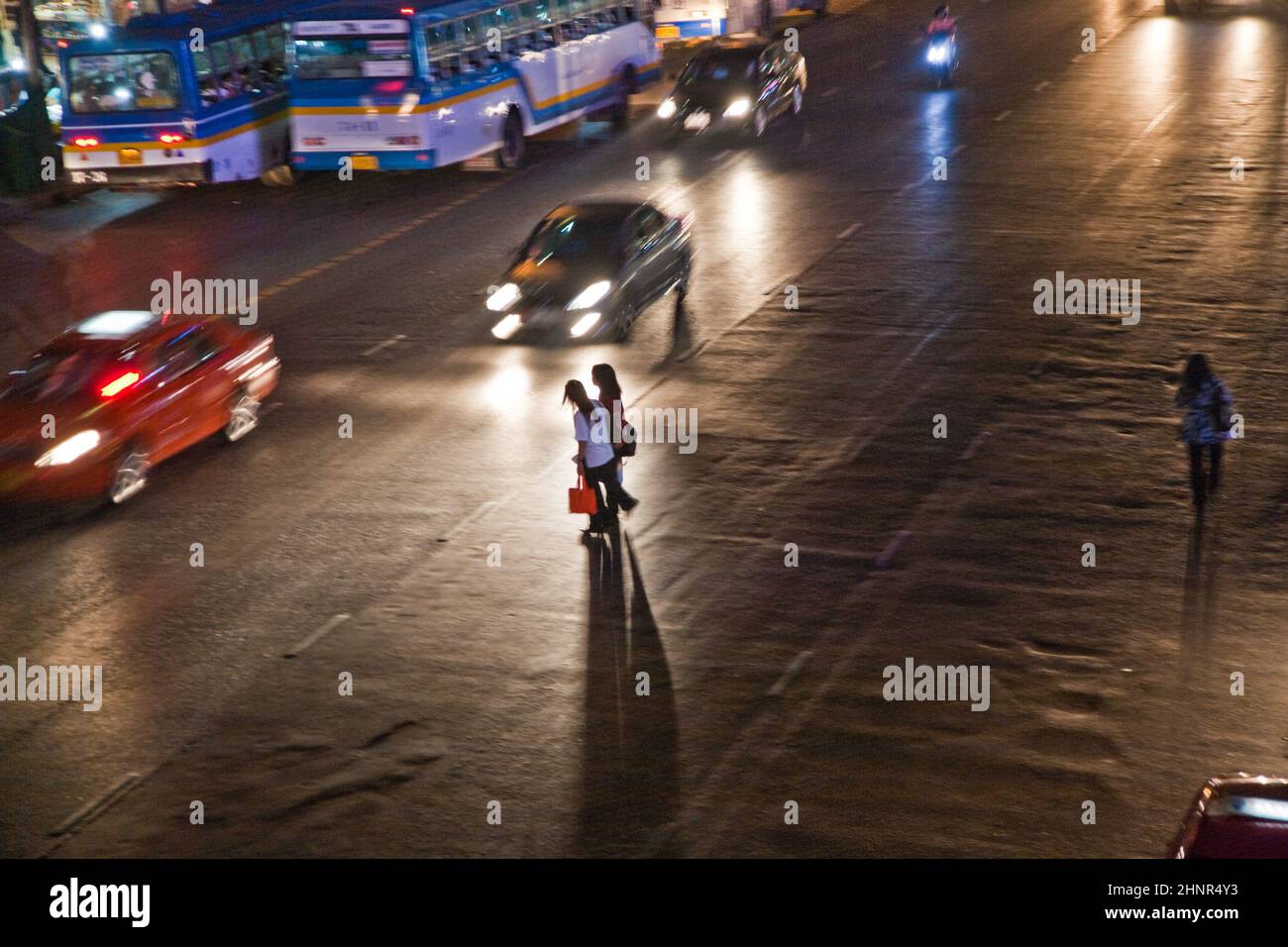 Frauen überqueren nachts eine Hauptstraße in Bangkok Stockfoto
