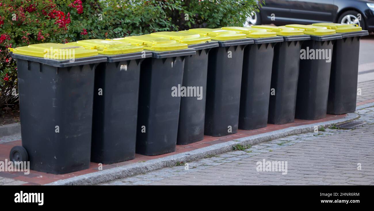 Mehrere Tonnen gelbe Mülltonnen für Plastikmüll auf einer Straße. Stockfoto