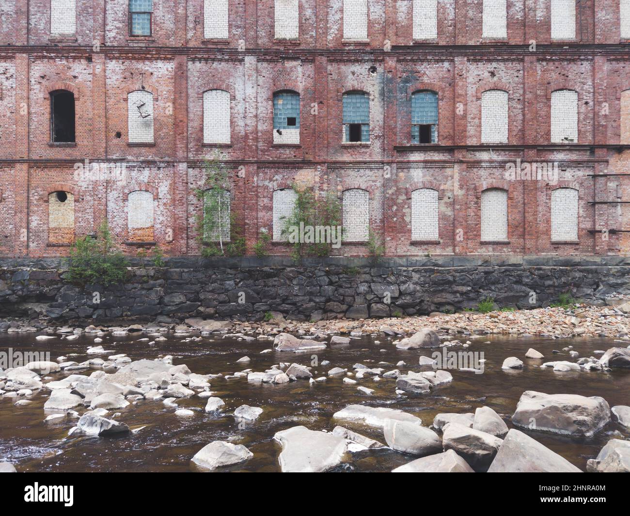 Verlassene Fabrik am Wasserrand. Altes Gebäude auf dem felsigen Fluss