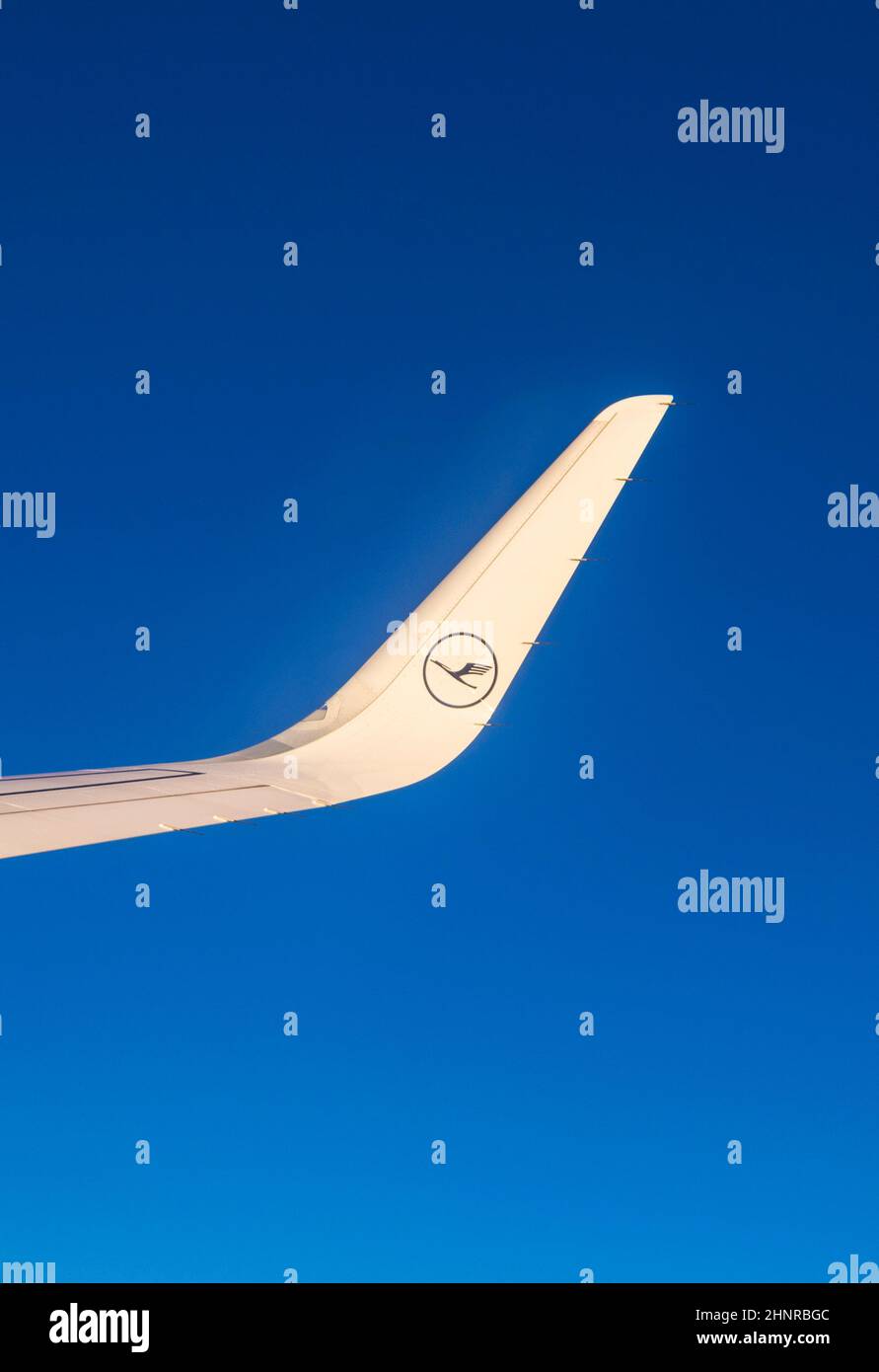 Flugzeugflügel mit lufthansa-Logo, der am Himmel bei Sonnenuntergang fliegt Stockfoto