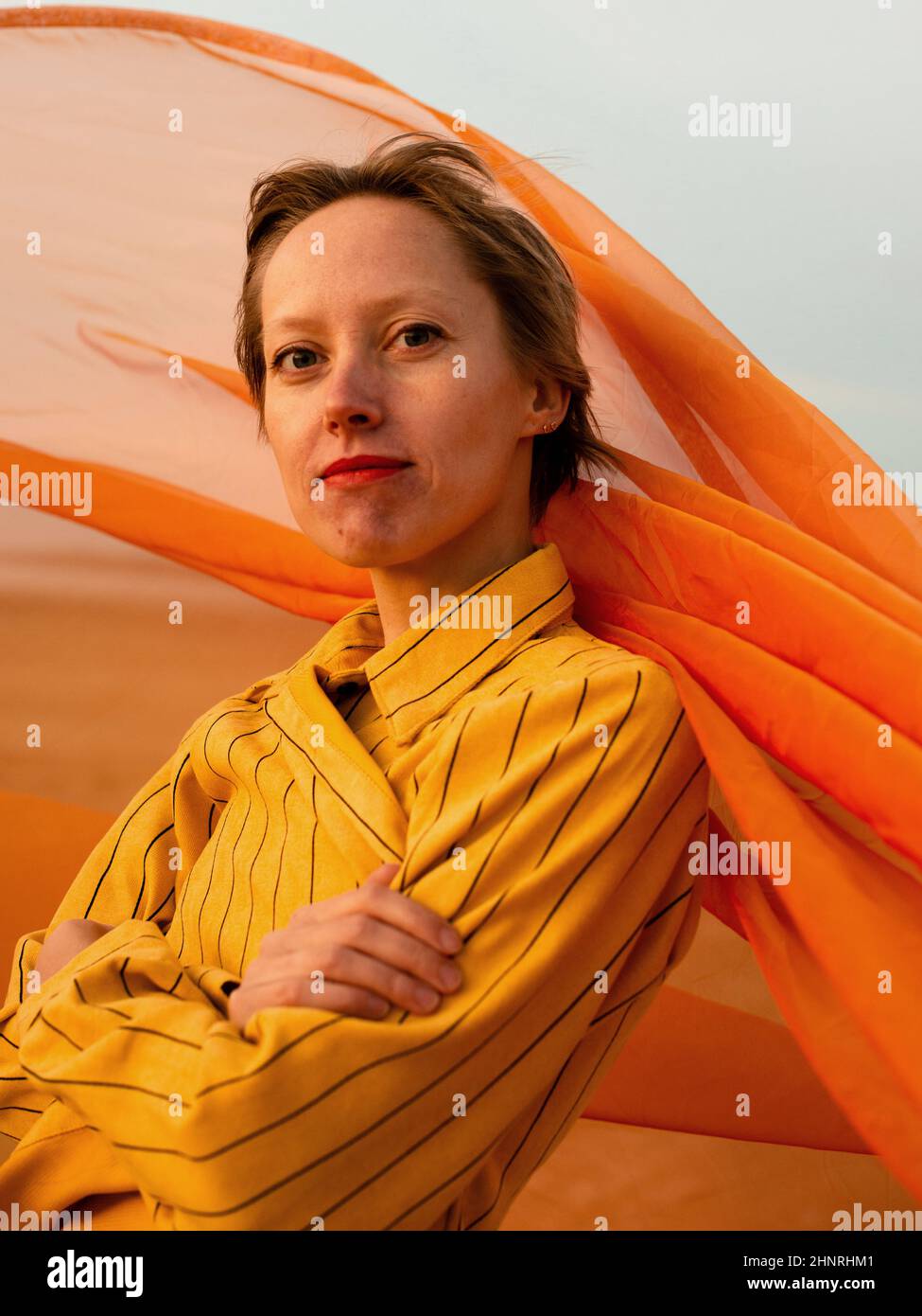 Porträt einer Frau mit orangefarbenem Tuch in der Wüste Stockfoto