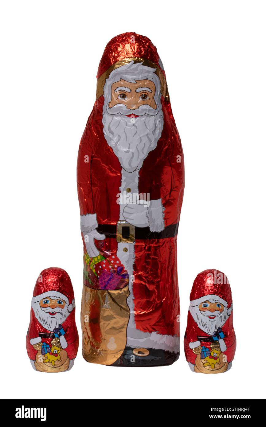 SchokoladenSanta isoliert. Nahaufnahme von drei fröhlich eingewickelten Schokoladen-Weihnachtsmann oder der guten Nikolaus-Figur auf weißem Hintergrund. Makrofotografie. Stockfoto