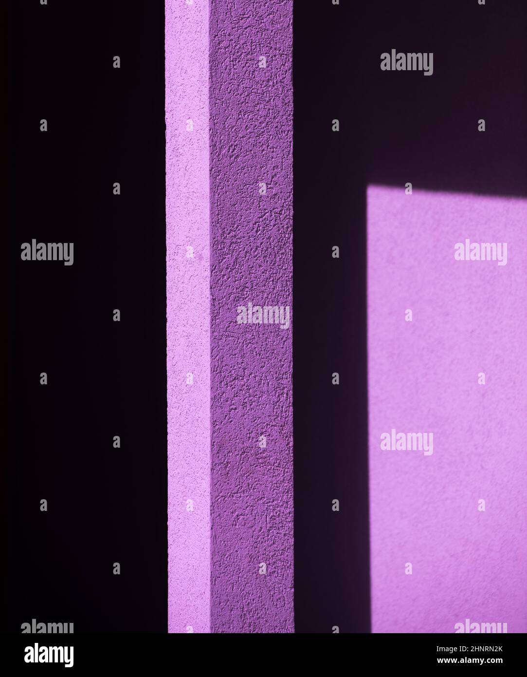 Geometrische Formen Winkel von Schatten, die auf das helle violette Zementbetongebäude oder die Hauswand im Nachmittagssonne im Freien gegossen werden, rechtwinklig Stockfoto