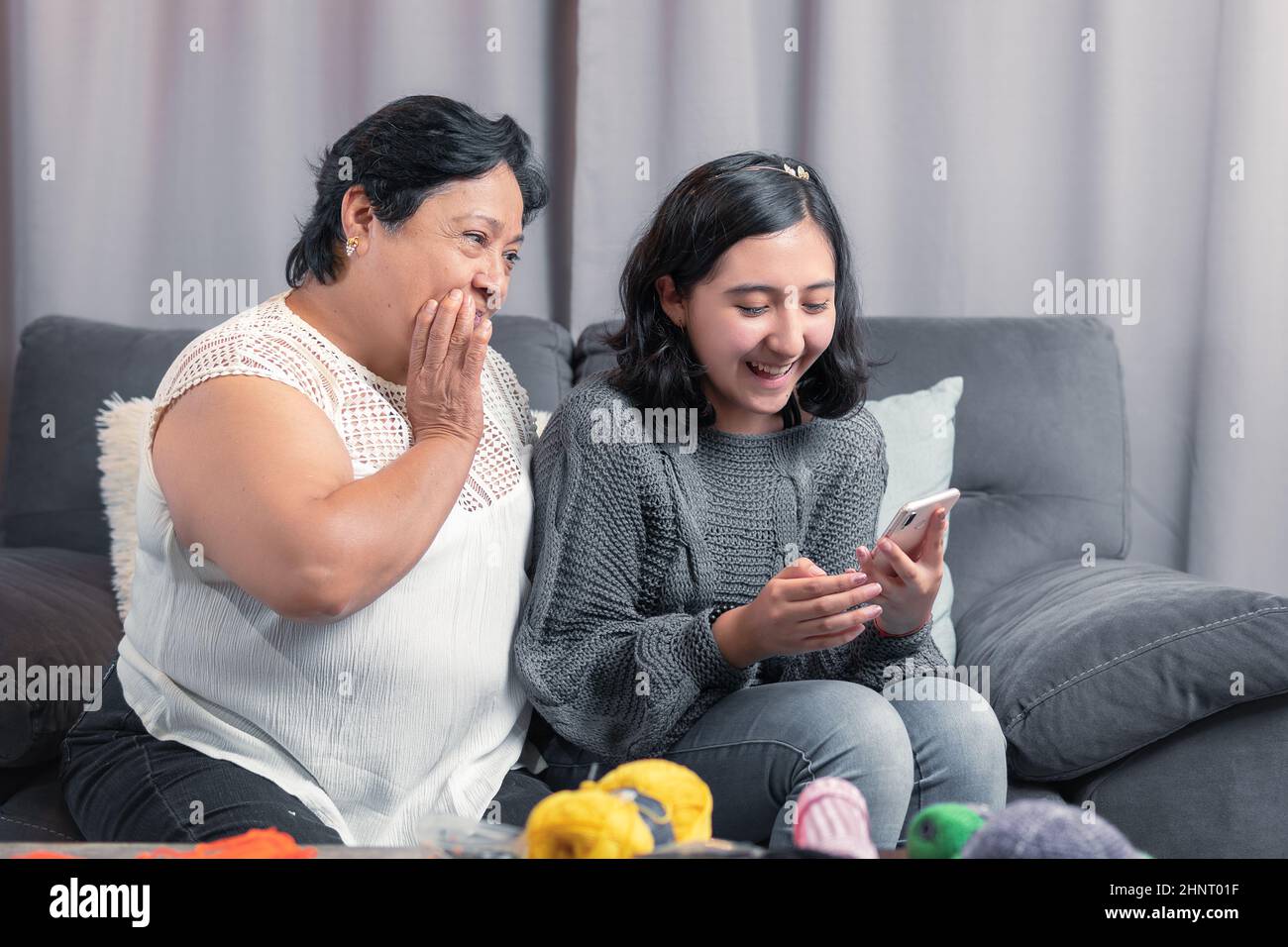 Ältere Frau 60 Jahre alte lateinische Großmutter mit Handy und Spaß mit ihrer Enkelin fotografieren und Videos ansehen Stockfoto