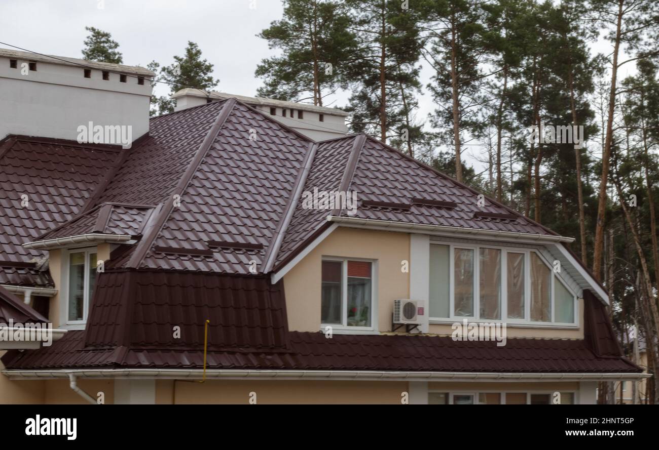 Dach auf Wohnimmobilien mit neuen braunen Wellblech-Dachziegeln. Modernes Metalldach. Metalldach. Stockfoto