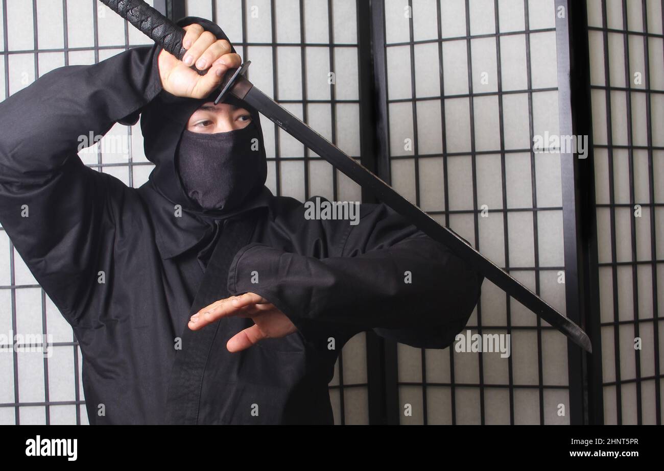 Asian man trägt Ninja Kostüm und hält Ninja Waffen Stockfoto