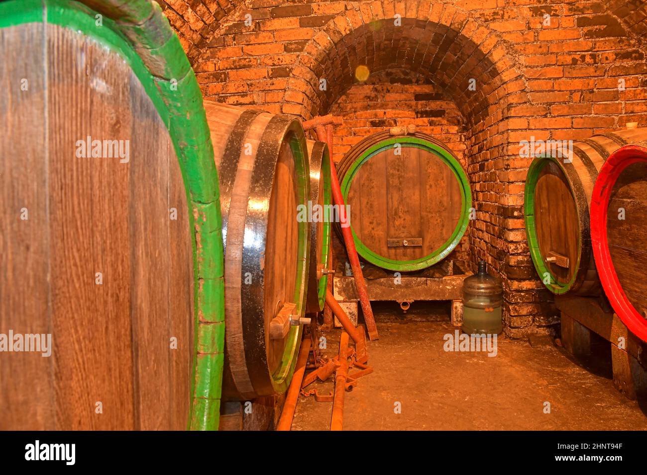 Weinfässer in einem Keller gestapelt. Fässer Wein in einem Weinkeller, einem alten Weinkeller mit gewölbten Ziegeldecken. Traditionelle Weinherstellung Stockfoto