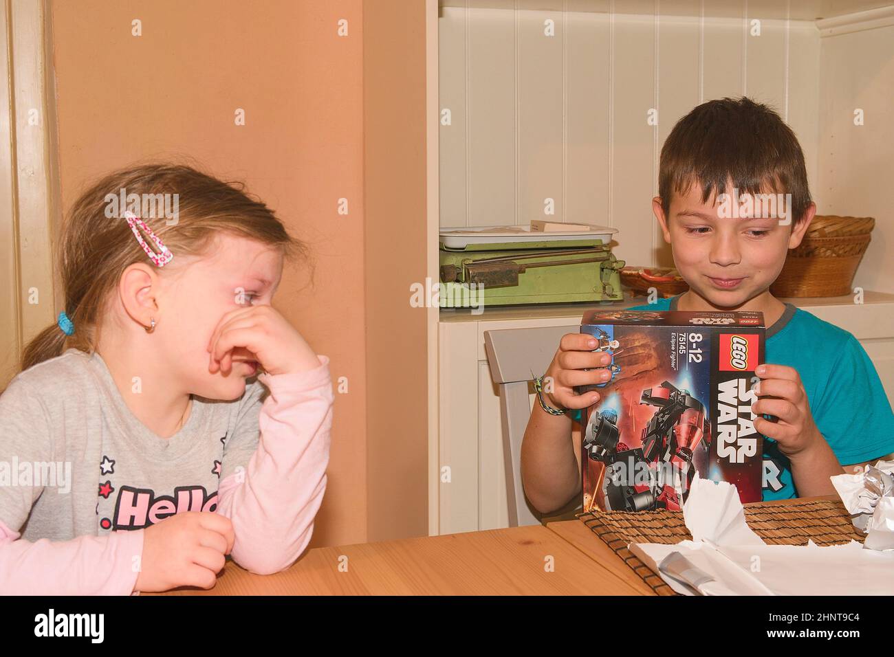 Junge feiert den neunten Geburtstag. Das Geburtstagsgeschenk ist LEGO Star Wars. Bruder und seine enttäuschte Schwester. Stockfoto