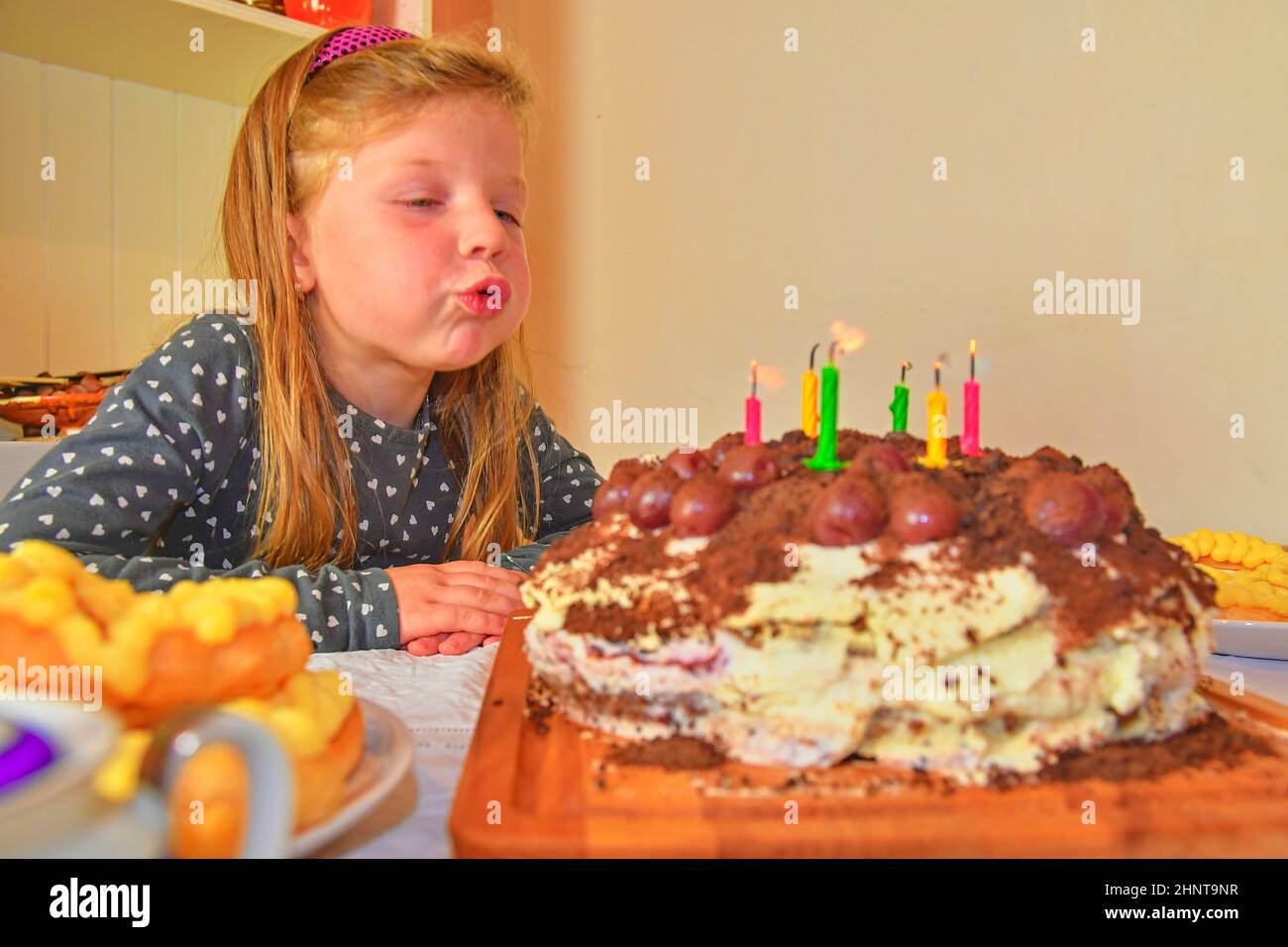 Kleine Mädchen bläst die Kerzen auf dem Geburtstagskuchen. Kleine Mädchen ihre sechs Geburtstag feiern. Geburtstag Kuchen und kleine Mädchen Stockfoto