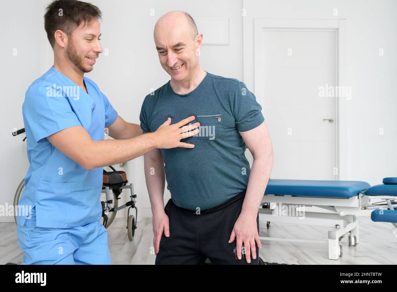 Physiotherapeut hilft behinderten männlichen Patienten, Unterstützung während der Bewegungstherapie. Stockfoto