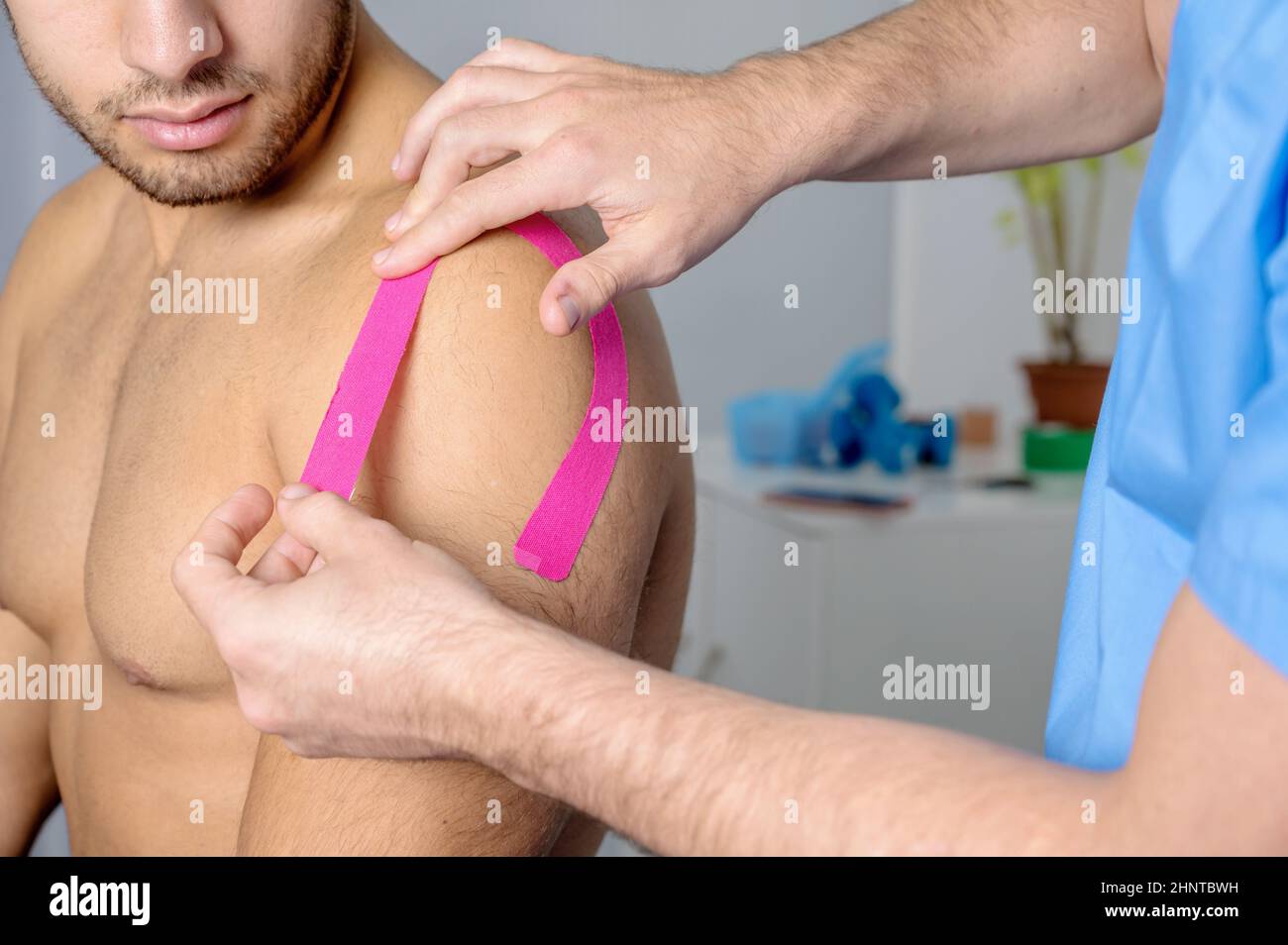 Physiotherapeut, der Kinesioband auf die Schulter des männlichen Patienten aufklebt. Kinesiologie, Physiotherapie, Rehabilitationskonzept. Nahaufnahme Stockfoto