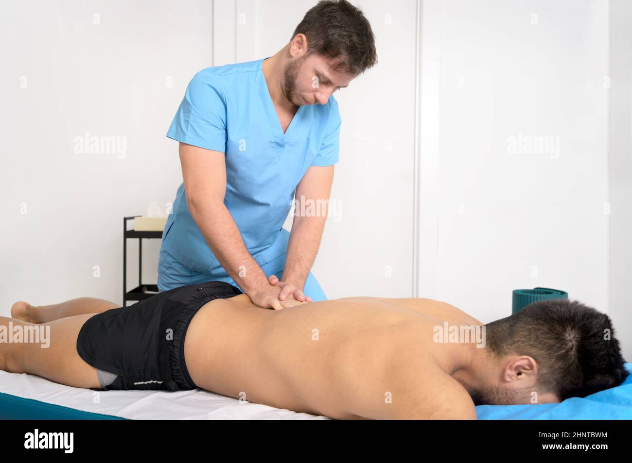Physiotherapeut massiert den Rücken eines jungen Sportlers in der Rehabilitationsklinik. Stockfoto