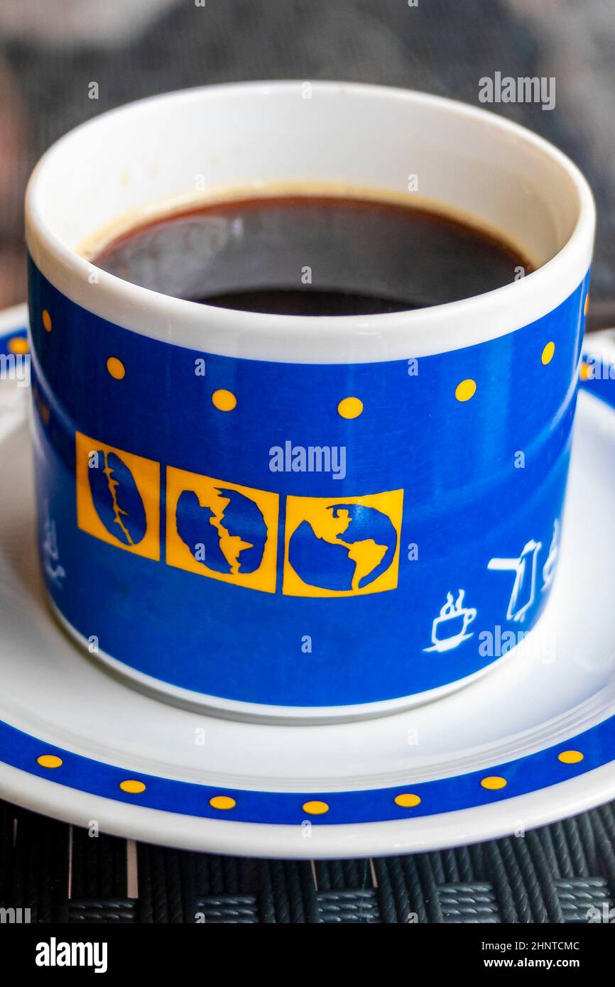 Schwarzer Kaffee in einer blauen Tasse mit Weltgloben, Thailand. Stockfoto