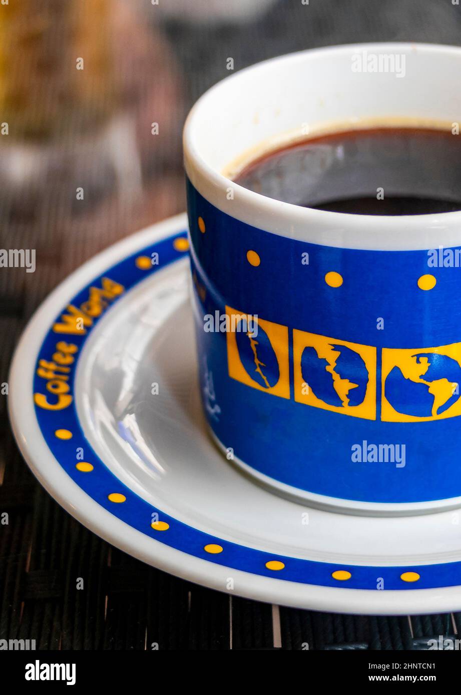 Schwarzer Kaffee in einer blauen Tasse mit Weltgloben, Thailand. Stockfoto
