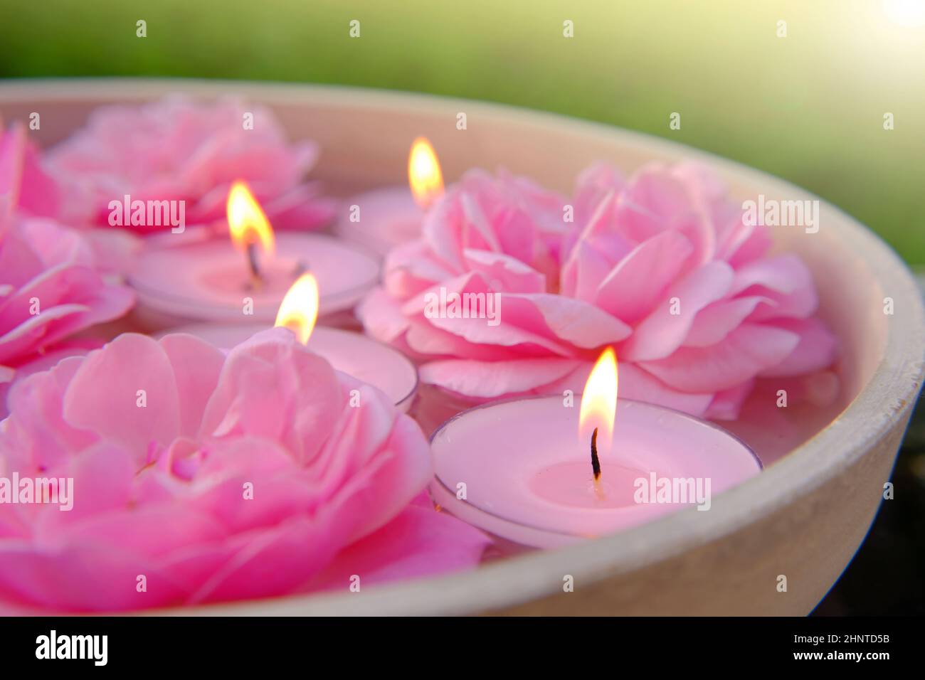 Rosenkerzen.Rosa brennende Kerzen und rosa Rosen im Wasser.Aromatherapie und Spa.Kerzenflamme. Kerzen Hintergrund.brennende Kerzen Set Stockfoto
