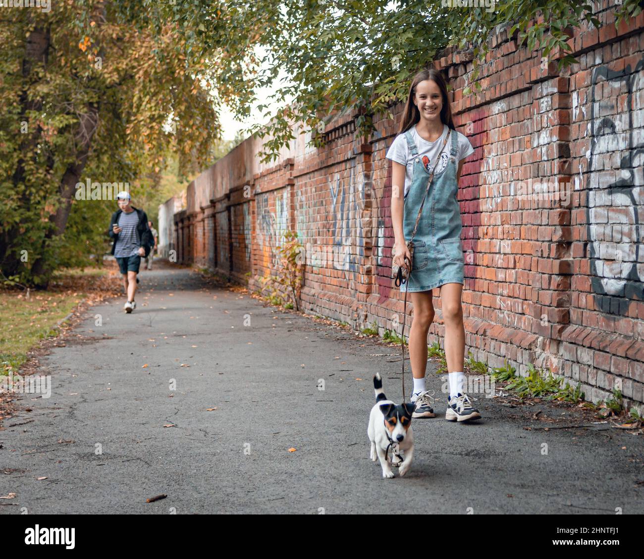 30th. August. Russland, Tomsk, Mädchen mit kleinem Hund gehen an der Wand auf der Straße Stockfoto