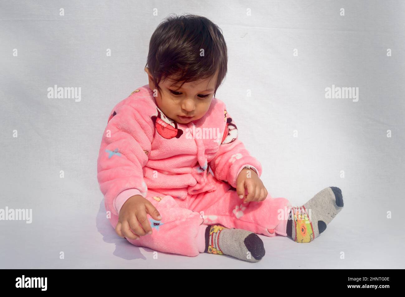 Nahaufnahme Porträt von Happy Baby trägt rosa Samt warme Kleidung auf weißem Hintergrund. Niedliches Baby im Bodysuit Herbst- oder Wintermode-Outfit an einem sonnigen Tag. Ganz kleiner Junge. Speicherplatz kopieren. Vorderansicht Stockfoto