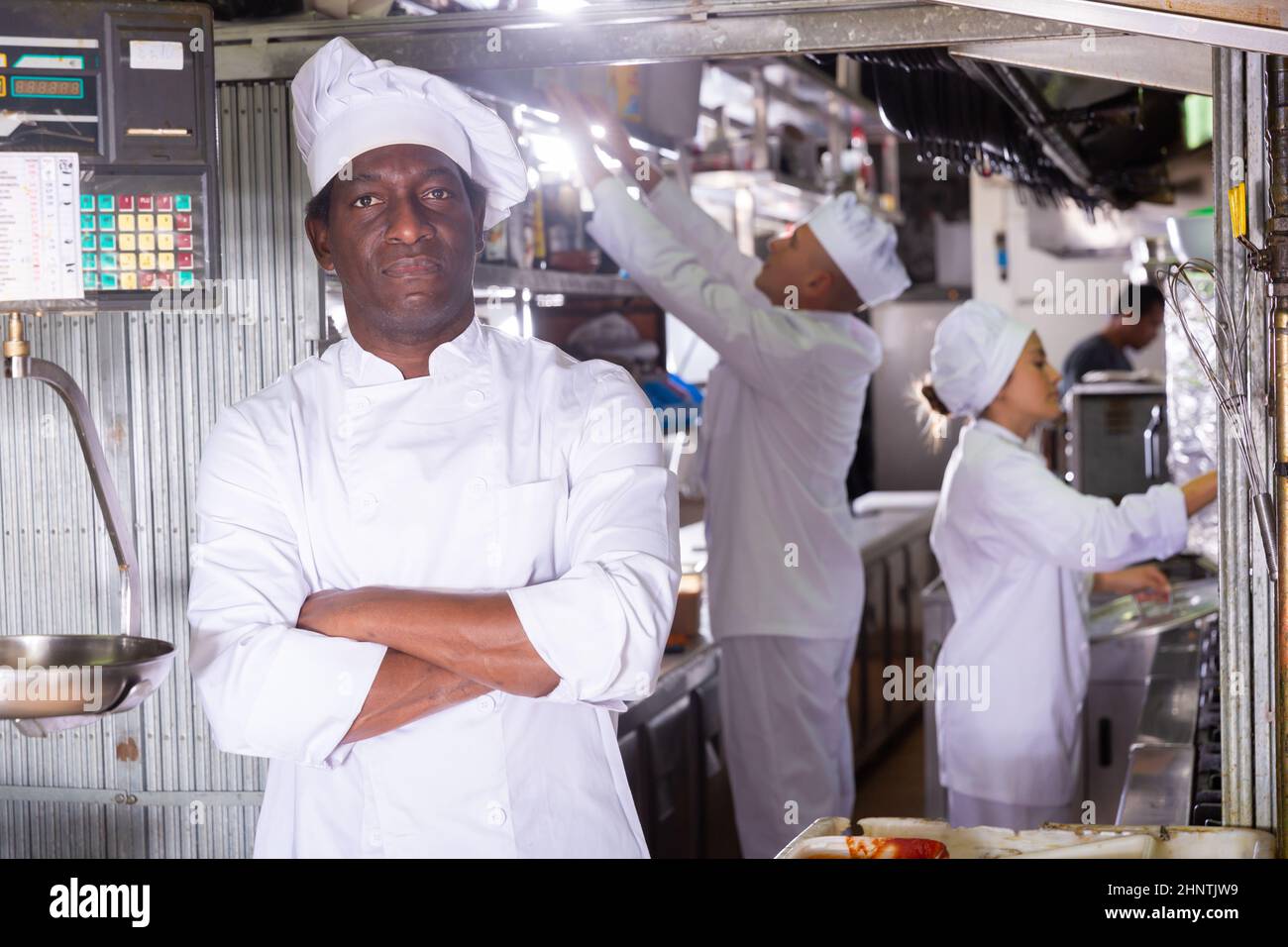 Porträt eines lächelnden männlichen Küchenchefs, der in einer modernen Küche steht Stockfoto
