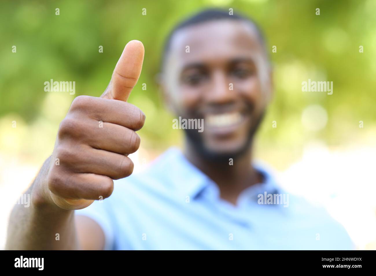 Glücklicher Mann mit schwarzer Haut, der Daumen nach oben in einem Park gestikuliert Stockfoto