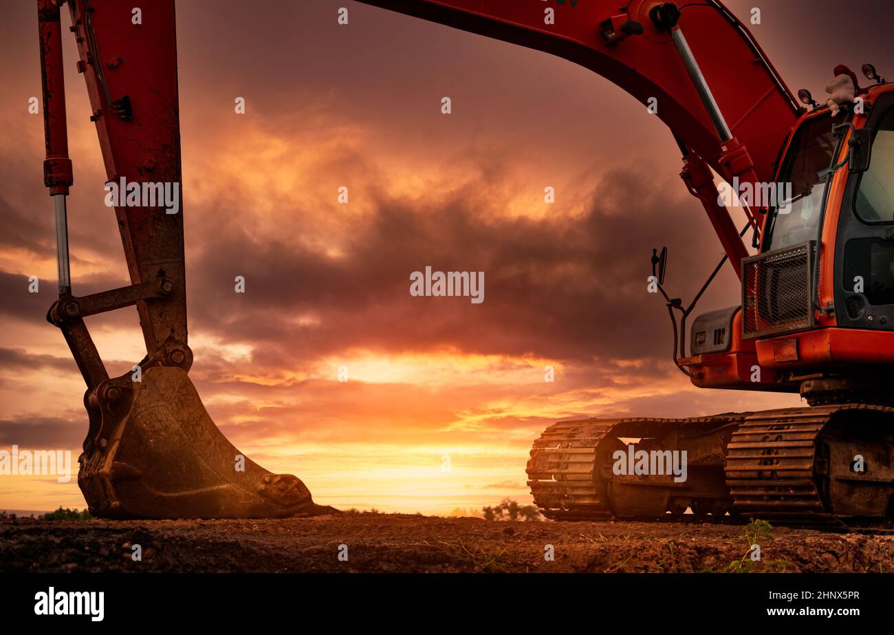 Baggerlader auf der Baustelle geparkt, nachdem Boden gegraben wurde. Bulldozer auf Sonnenuntergang Himmel und Wolken Hintergrund. Bagger nach der Arbeit. Erdbeweger an der Kons Stockfoto