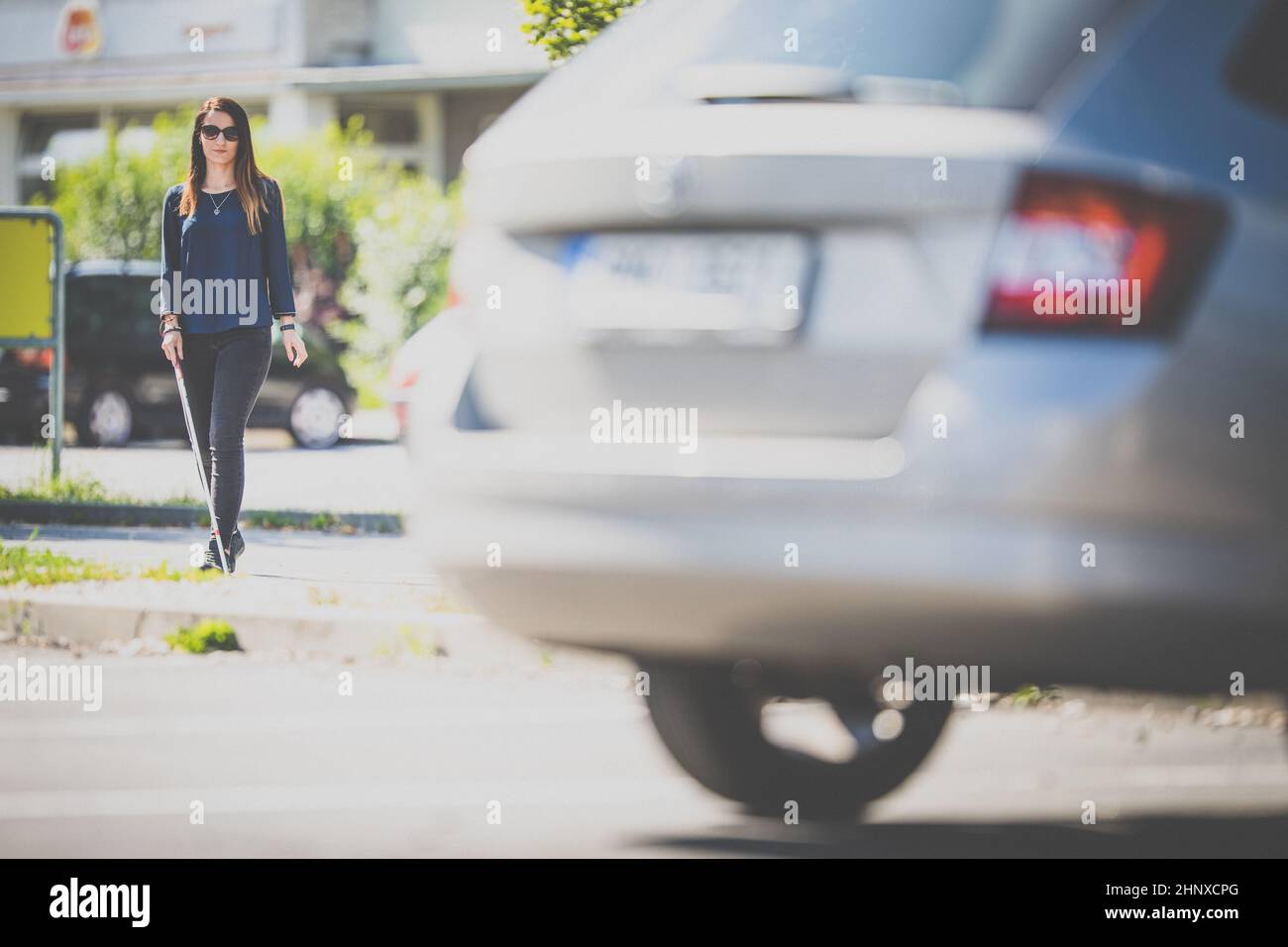 Blinde Frau, die auf den Straßen der Stadt geht, mit ihrem weißen Stock, um den städtischen Raum besser zu navigieren und sicher an ihr Ziel zu gelangen Stockfoto