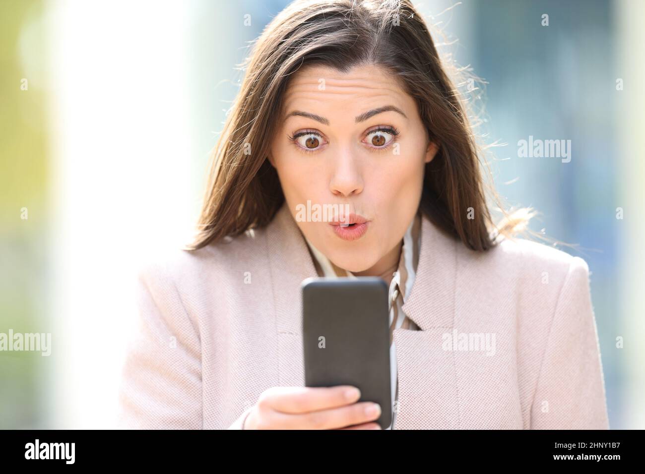 Frontansicht Porträt eines überraschten Executive prüft Smartphone-Inhalte auf der Straße Stockfoto