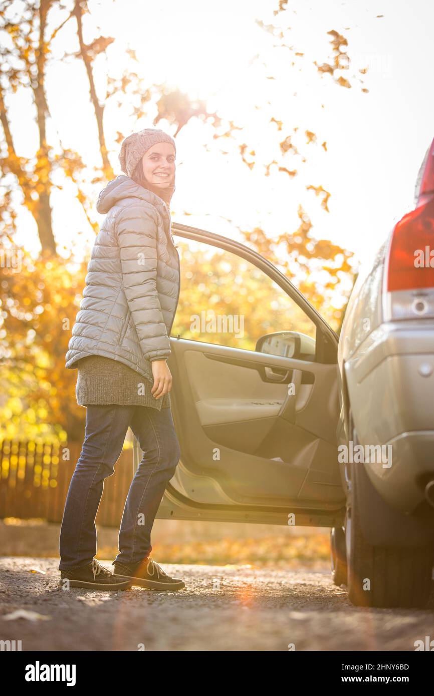 Hübsche junge Frau an ihrem Auto bereit für ihren täglichen Weg zur Arbeit Stockfoto