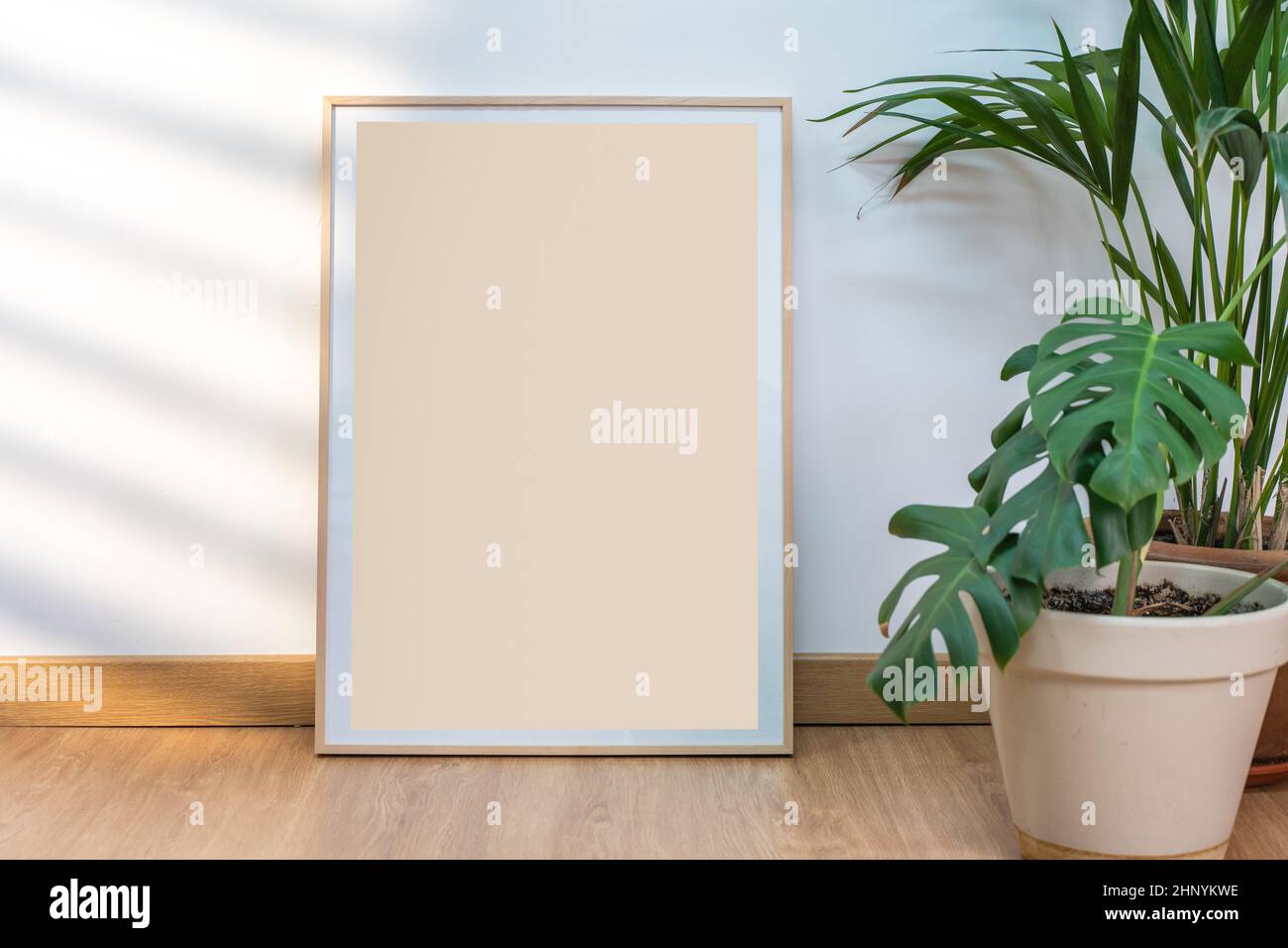 Boho Holzrahmen vertikale Monographie Mockup auf sauberen weißen Wänden, Pflanzen und Sonnenstrahlen. Stockfoto