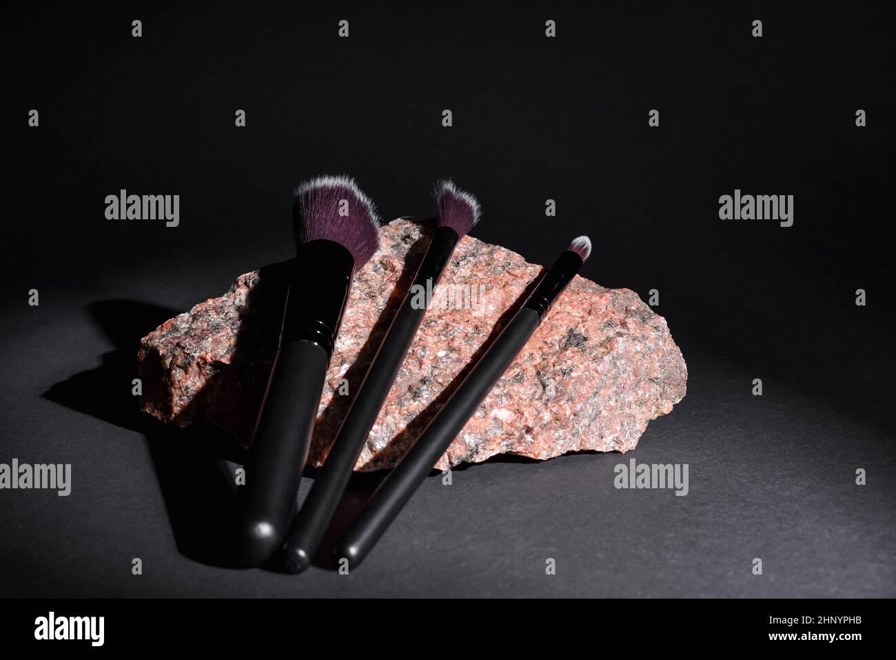 Make-up Kosmetikbürsten liegen auf Granitstein auf schwarzem Hintergrund. Set aus verschiedenen kosmetischen Bürsten für Make-up Künstler. Stockfoto