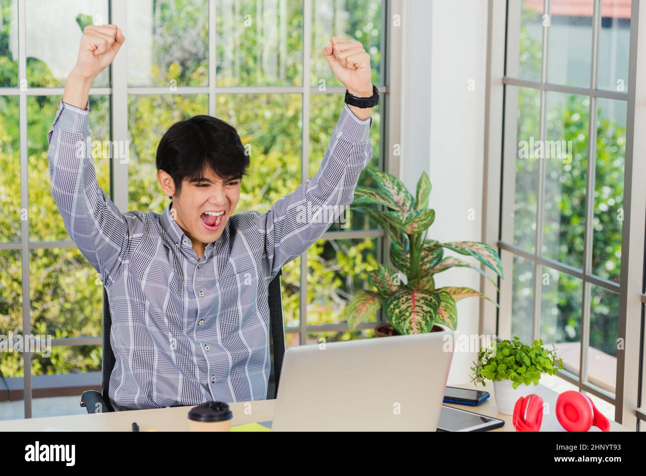 Ja! Glücklich aufgeregt asiatischen Mann hob seinen Arm bis zu feiern Erfolg. Junger Geschäftsmann mit Laptop-Computer an der Büroschreibtisch er froh, wieder Stockfoto