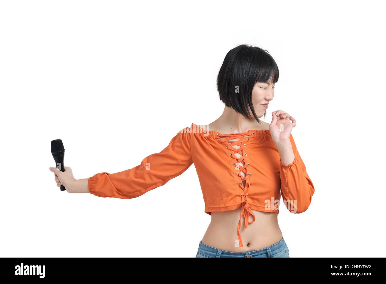 Junge asiatische Frau, die sich von einem lauten Ton mit Mikrofon, isoliert, zurückschölt. Stockfoto