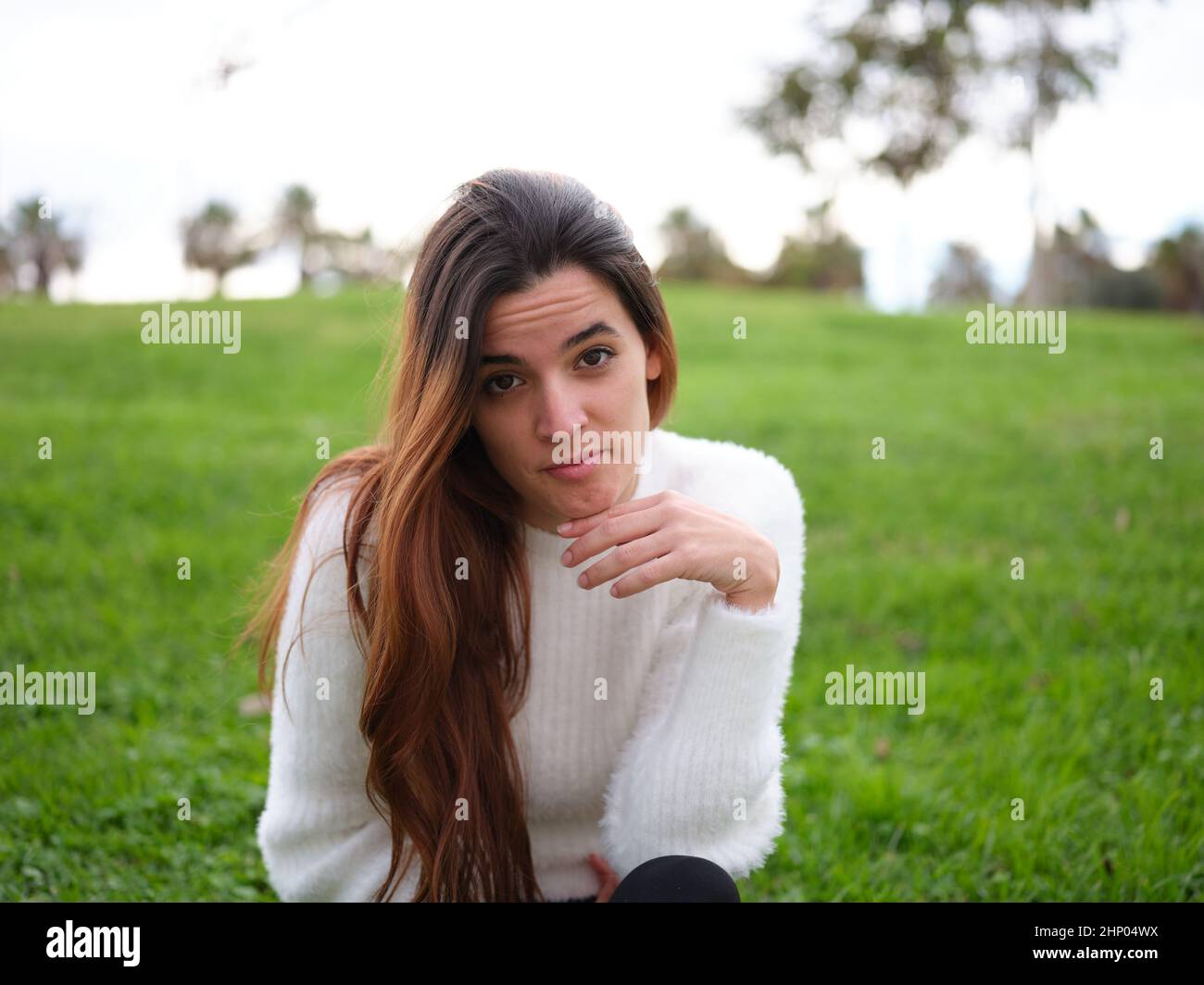 Eine junge Frau im Park, die die Kamera anschaut, fühlt sich vermisst. Stockfoto