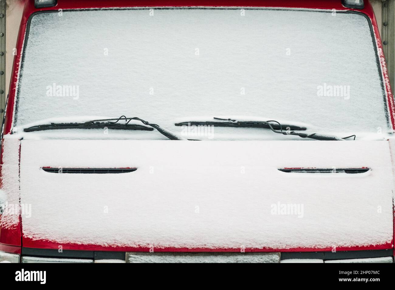 Die Windschutzscheibe des Autos mit Schnee bedeckt. Scheibenwischer sind wie Augenbrauen über den Augen. Stockfoto