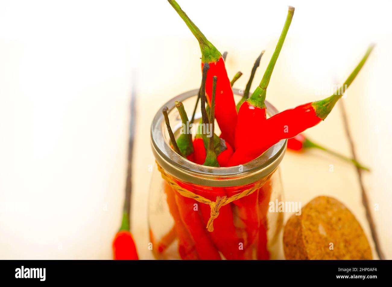 rote Chilischoten auf ein Glas über weiße rustikalen Holztisch Stockfoto