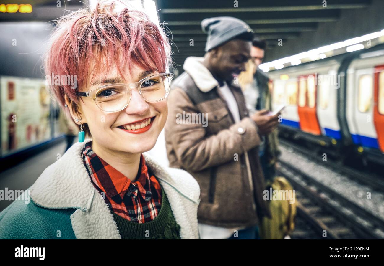 Junge Frau mit rosa Haaren und eine Gruppe von multirassischen Hipster-Freunden, die am U-Bahnhof der U-Bahn auf den Zug warten - Urban Friendship Concept with Young Peo Stockfoto