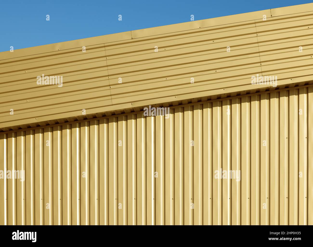 Hintergrund Textur von goldenem Aluminium gewellten Metallwand unter blauem Himmel Stockfoto