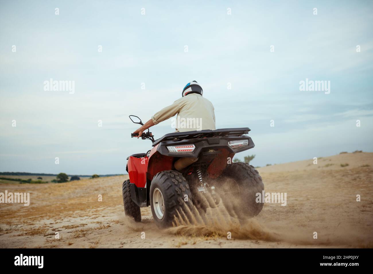 Ein atv-Fahrer, der in der Wüste rast, bergab im Wüstensand fährt, Actionblick. Mann auf dem Quad, Sandrennen, Dünensafari an heißen sonnigen Tagen, 4x4 e Stockfoto