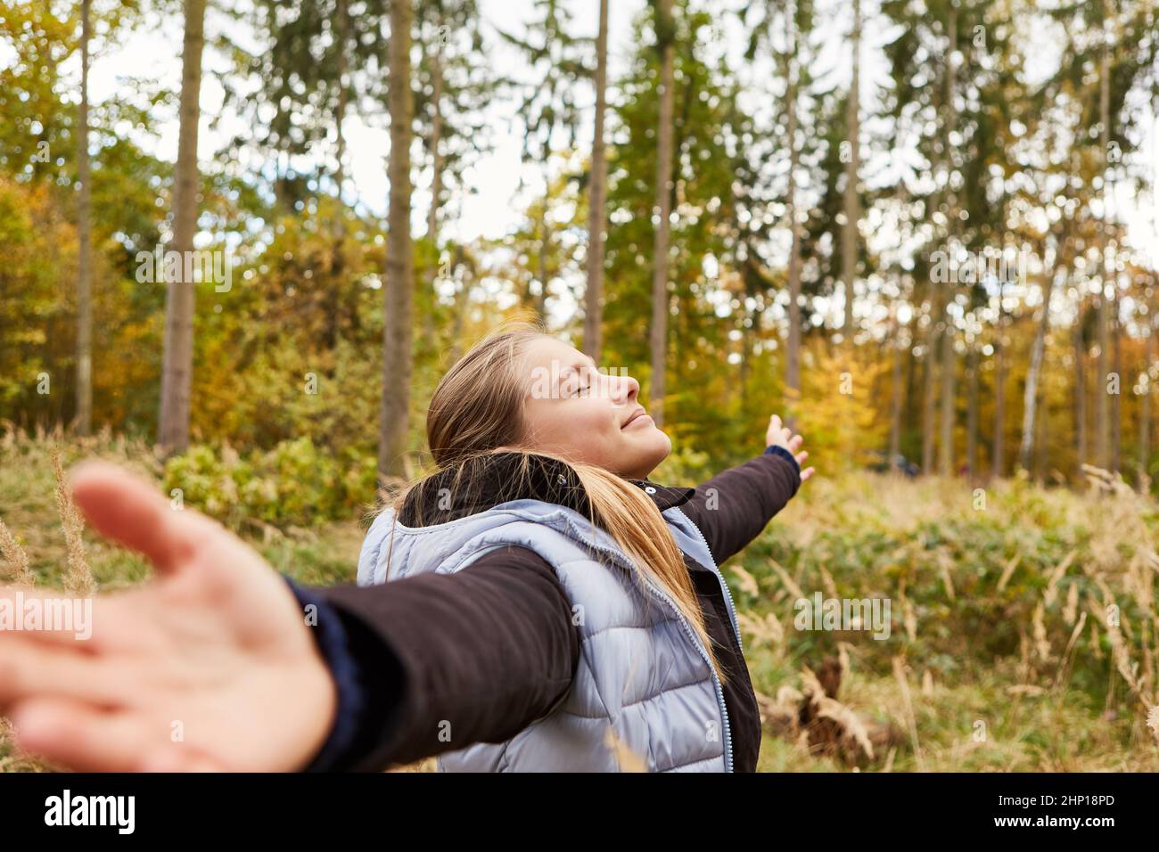 Glückliche, entspannte Frau mit ausgestreckten Armen und Atemübungen im Wald im Freien Stockfoto