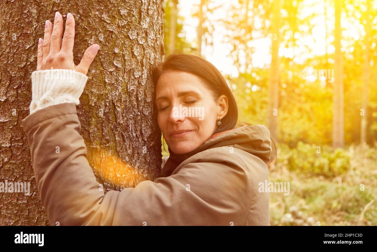 Frau umarmt den Baum im Wald zur Entspannung als ein Konzept der Nähe zur Natur Stockfoto