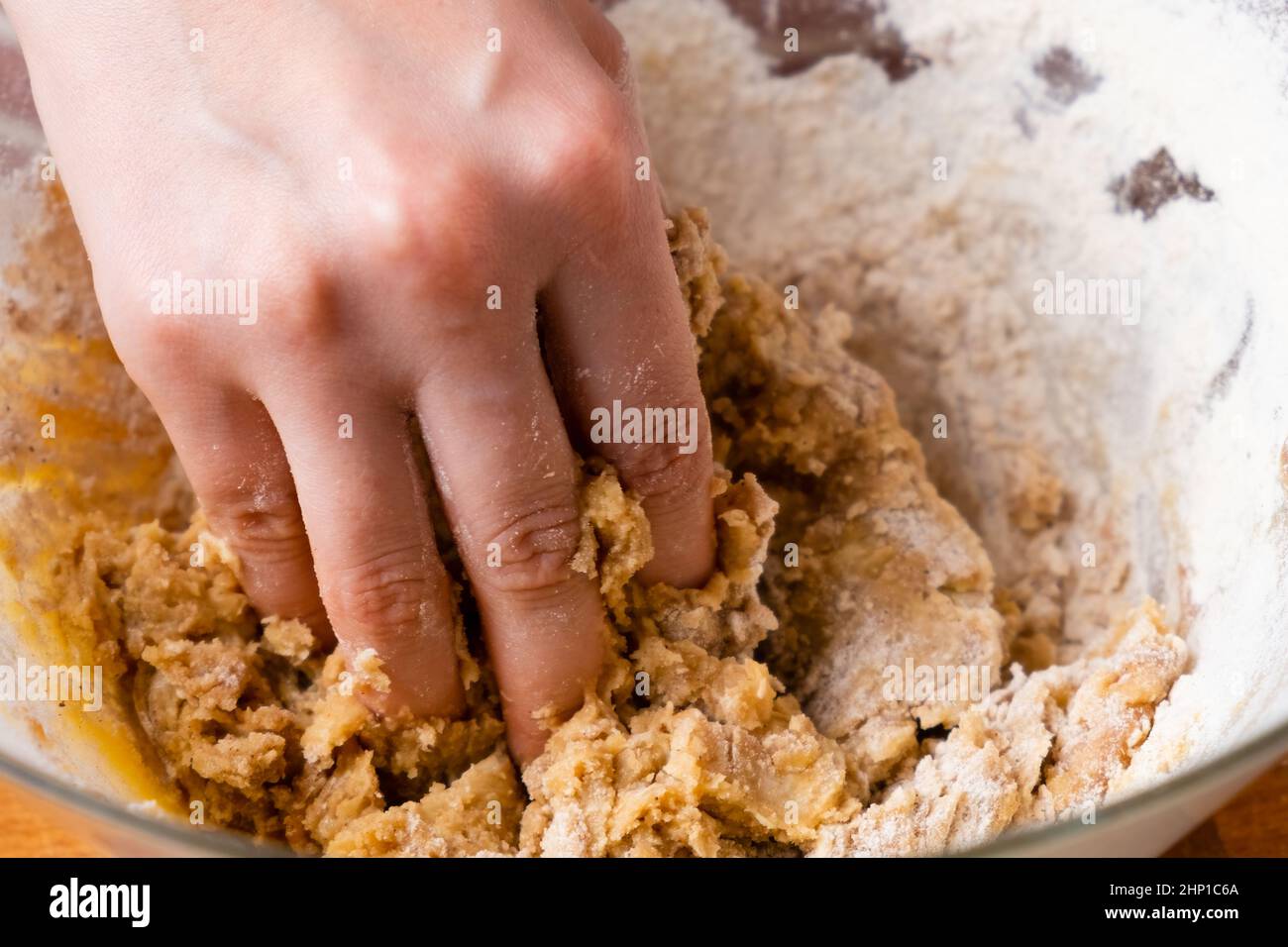 Nahaufnahme der Hände einer Bäckerin, die den Teig in der Rührschüssel knetet. Hausgemachtes Gebäck für Kuchen oder Kekse. Stockfoto