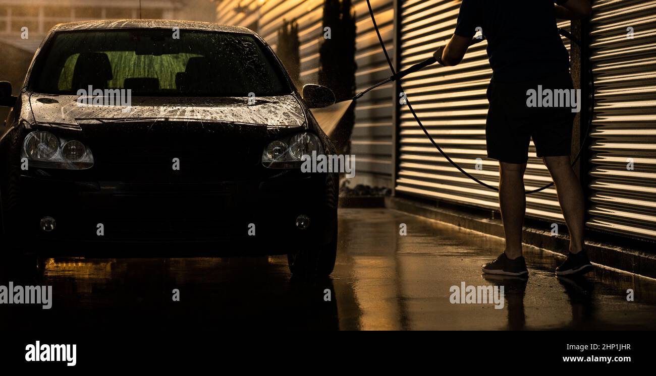 Junger Mann wäscht sein geliebtes Auto sorgfältig in einem Handbuch Autowäsche, um Schäden zu vermeiden und Detail es richtig Stockfoto