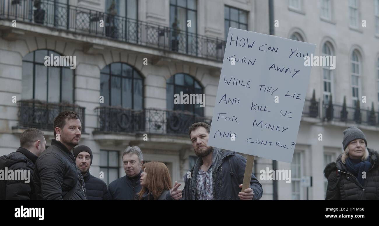London, Großbritannien - 01 22 2022: Mann protestiert am Portland Place mit einem Schild: ‘Wie kannst du dich abwenden, während sie lügen und uns für Geld und Kontrolle töten'. Stockfoto