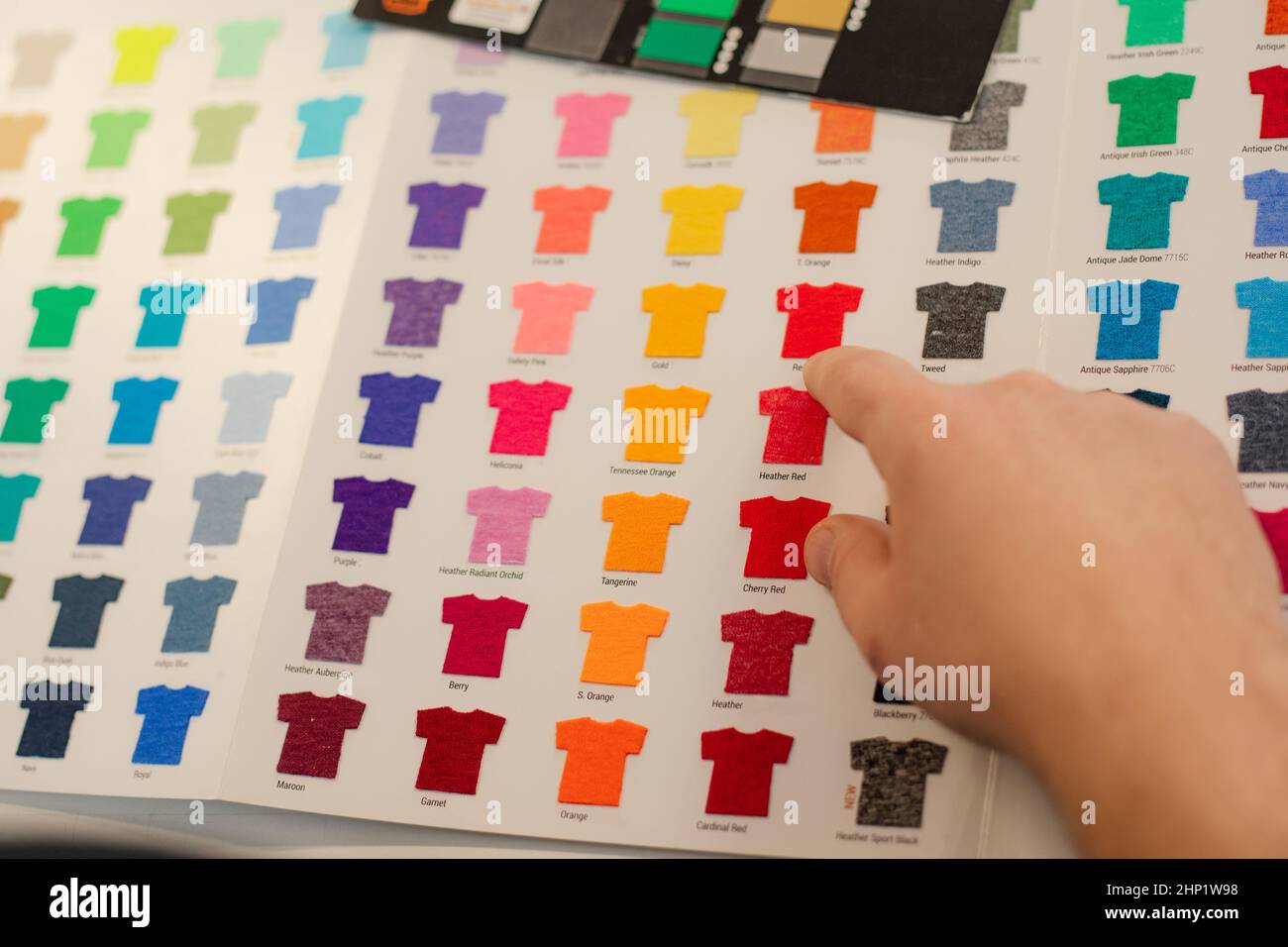 Cropped Mann Hand Auswahl Muster Vorlagen mehrfarbige Werbung T-Shirts Palette Film Membran. Textilproduktion Stockfoto