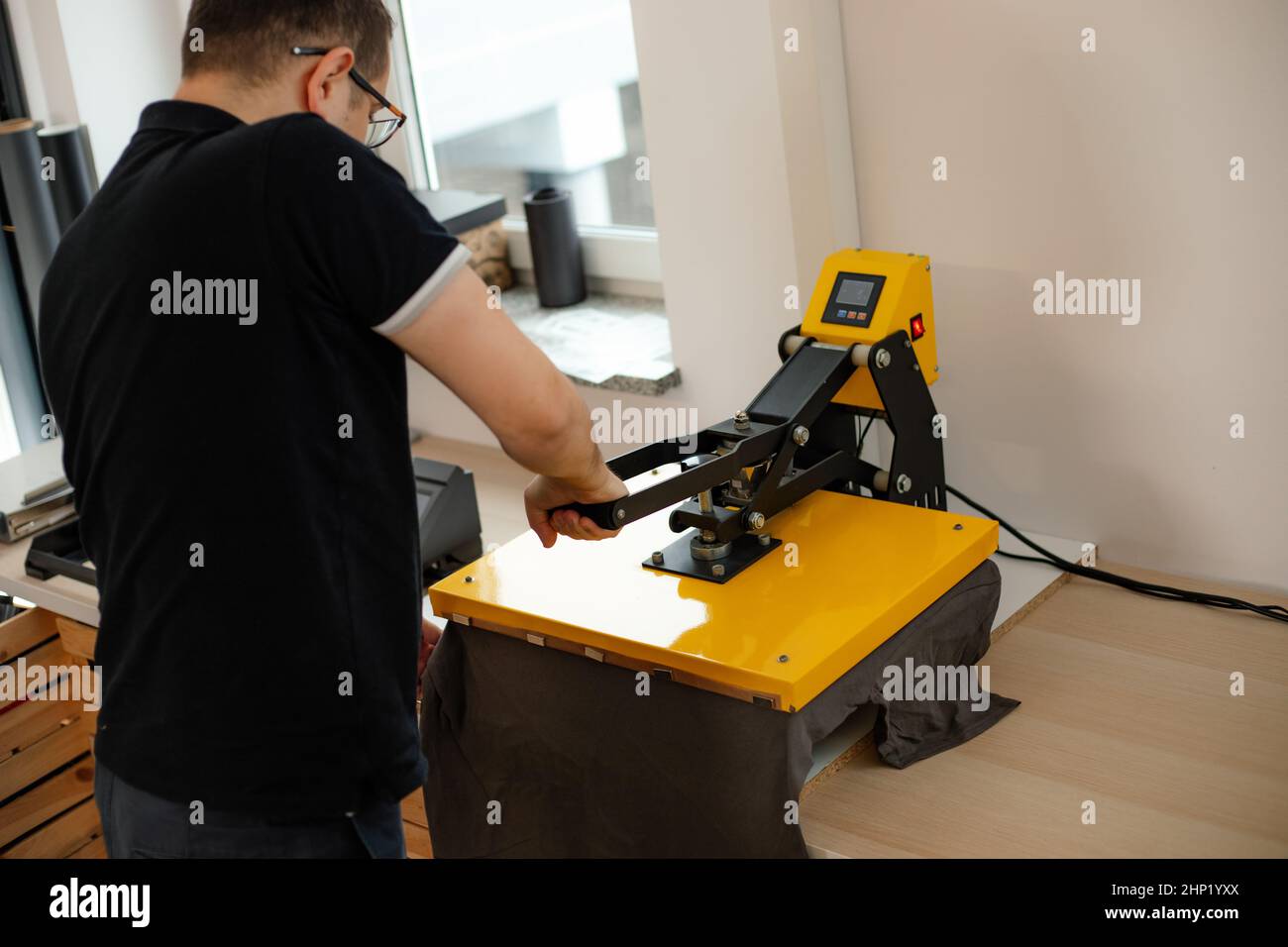 Mann Arbeiter Brille zurück mit Wärme thermischen Textil Anwendung Transfermaschine. Drucken Anwendung Kunst Design T-Shirt Stockfoto